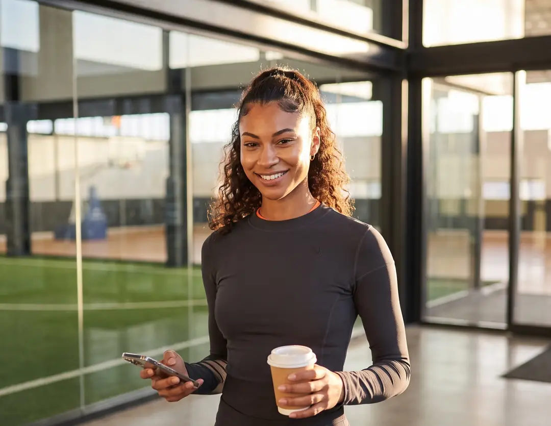 Sports facility director walking through the lobby in the morning with her phone and coffee